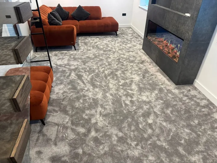 Grey carpet fitted in a living room with rust-coloured seating and a contemporary fireplace