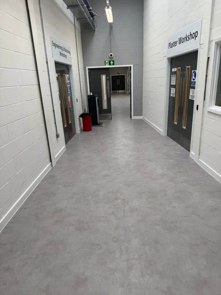 Grey flooring fitted along a corridor between workshops